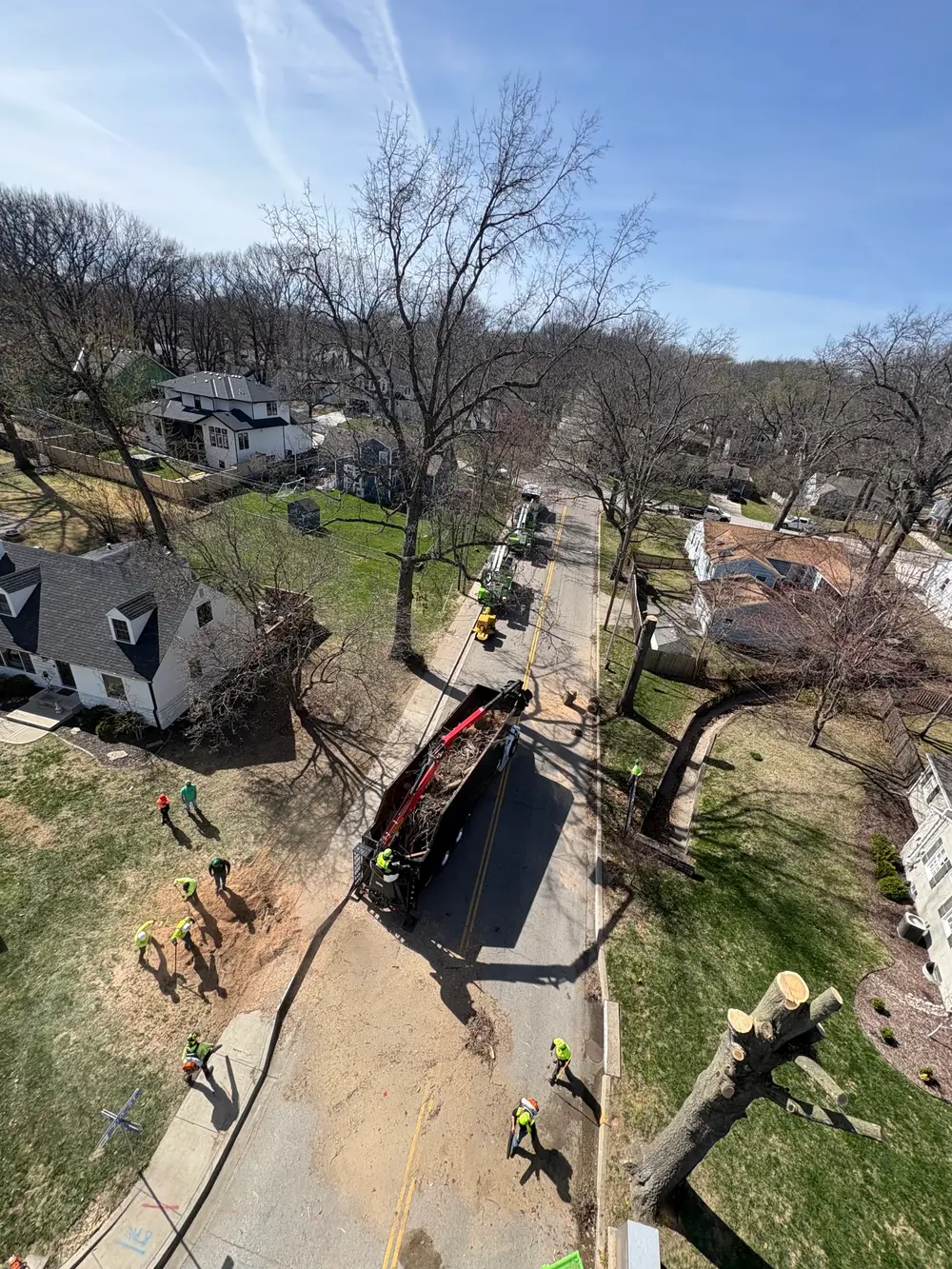 Overhead view of the crew and grapple truck taking down a tree on a residential street
